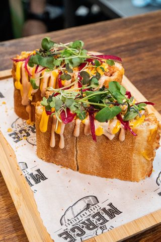 Two toasted brioche sandwiches with sauces and microgreens