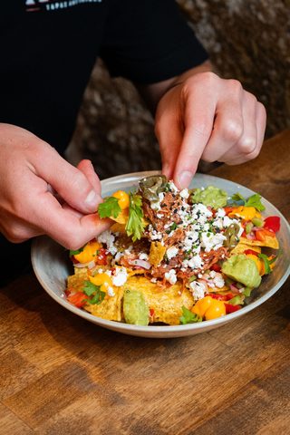 Bowl of nachos with cheese, guacamole and pico de gallo
