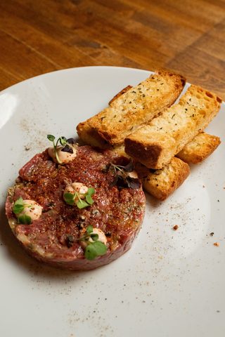 Steak tartare moulded into a round with toasted bread sticks
