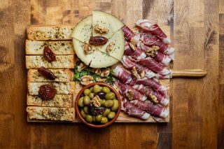 Board of cured ham, cheese, olives and toasted bread