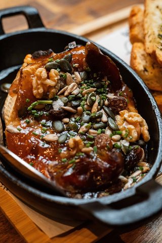 Melted cheese in a black pan topped with nuts and honey