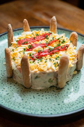 Ensaladilla rusa moulded into a cylinder with pepper strips and breadsticks